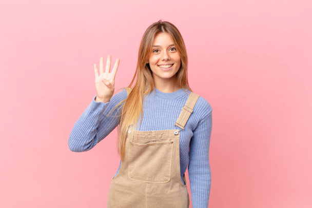 young woman smiling and looking friendly, showing number four - Foto, Imagem