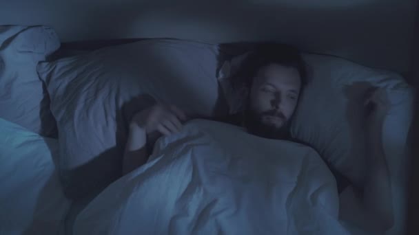 zaburzenia snu bezsenność noc irytowany mężczyzna w łóżku - Materiał filmowy, wideo