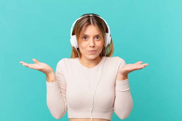 young woman with headphones feeling puzzled and confused and doubting - Foto, immagini