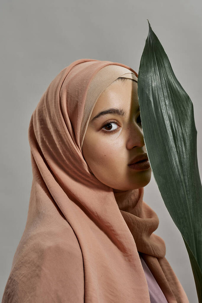 Young arabian girl in hijab next to green leaf - Valokuva, kuva