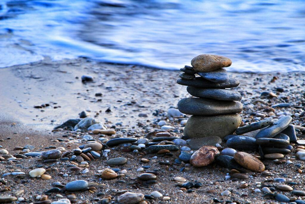 На заході сонця в Картахені круглі камені стояли на пляжі острова Плана. Хвилі на задньому плані. - Фото, зображення