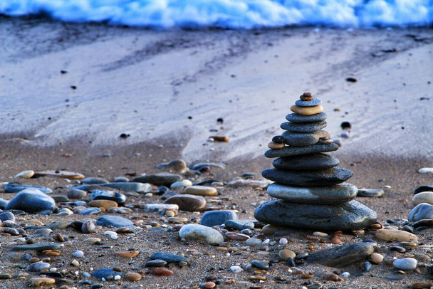 Piedras redondas apiladas en la playa Isla Plana al atardecer en Cartagena. Ondas en el fondo. - Foto, imagen