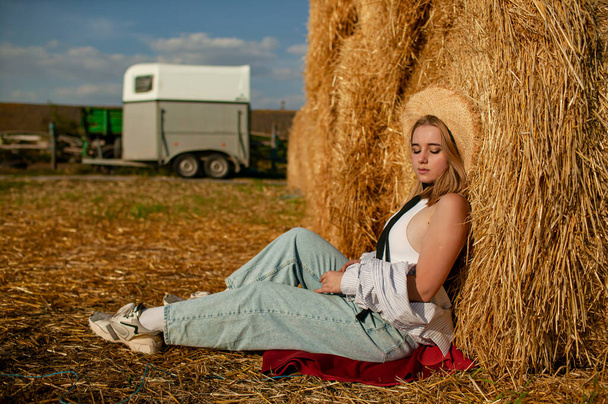 Young Beautiful Blonde Woman in a straw hat relaxing On Dry Hay In Summer - Photo, Image