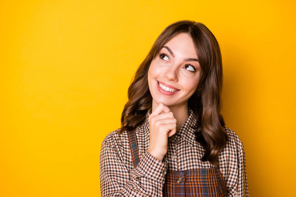 Photo of charming person hand on chin beaming smile look empty space wear plaid isolated on yellow color background - Photo, image