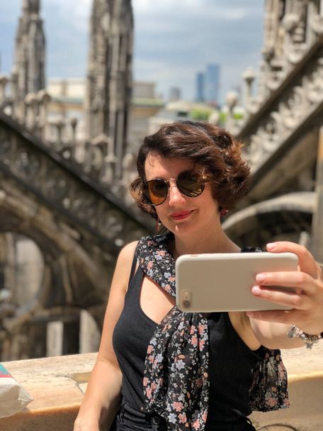 Young female traveler taking selfie above Milan Duomo. - 写真・画像