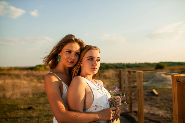 Two Young Pretty Blonde Women In Field Outdoor In Summer At Sunset - Фото, зображення