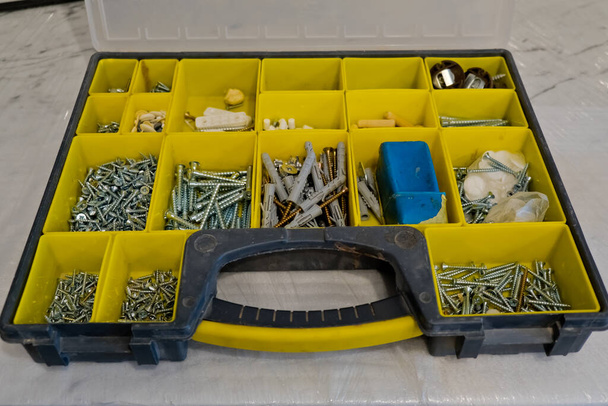 Small plastic yellow boxes with different screws and fasteners. Selective focus. - Photo, Image