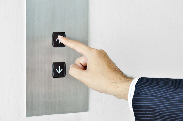 επιχειρηματίας χέρι αγγίζει ανεβαίνοντας σημάδι στον πίνακα ελέγχου του ανελκυστήρα - Φωτογραφία, εικόνα