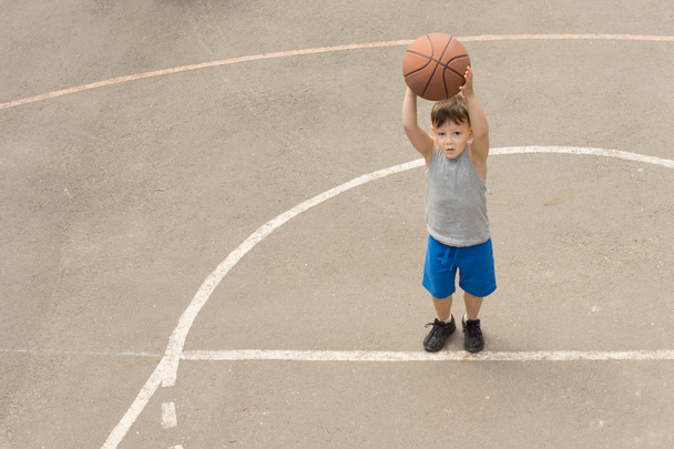 ładny chłopczyk praktykujących na boisko do koszykówki - Zdjęcie, obraz