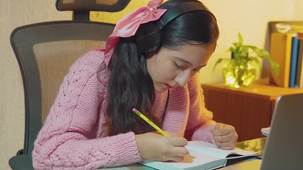 Hispánský teenager, středoškolský student nosí sluchátka na videohovory se svými vzdálenými učiteli, bere odlehlé hodiny z domova, zapisuje si do sešitu, co se učí ve svých virtuálních třídách - Záběry, video