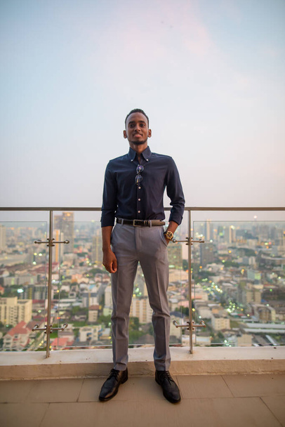 Portrait of handsome African businessman outdoors at rooftop in Bangkok, Thailand - Photo, Image