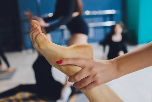 fitness, sport, training, gym and lifestyle concept - close up of people with trainer exercising and stretching leg in gym. - 写真・画像