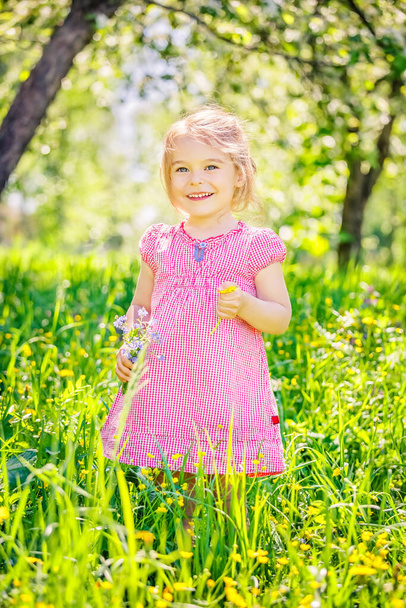 Happy little girl in spring garden - Foto, afbeelding