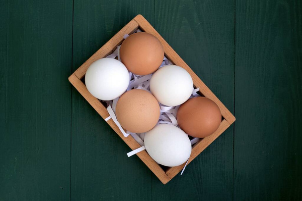 gele en witte eieren in een houten doos - Foto, afbeelding