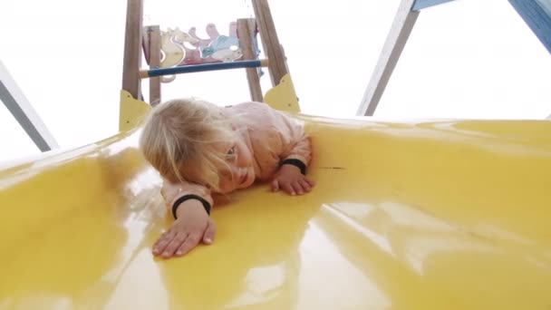 Petite fille excitée s'amuser sur la glissière dans l'aire de jeux - Séquence, vidéo
