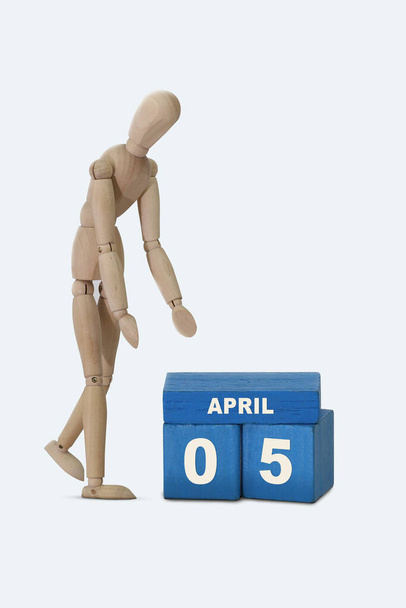 day of the month 05 April calendar A calendar date on blue cubes and a wooden man standing next to it. White background. - Photo, Image
