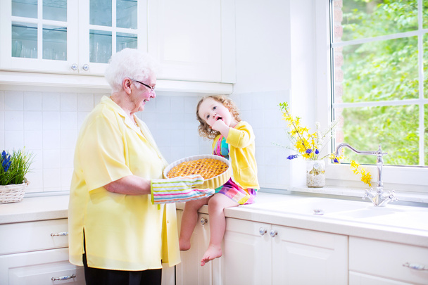 Felice nonna e bambina cuocere una torta in un kitche bianco
 - Foto, immagini