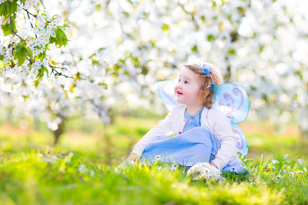 göndör kisgyermek lány tündér jelmez, gyümölcs kert játszik - Fotó, kép