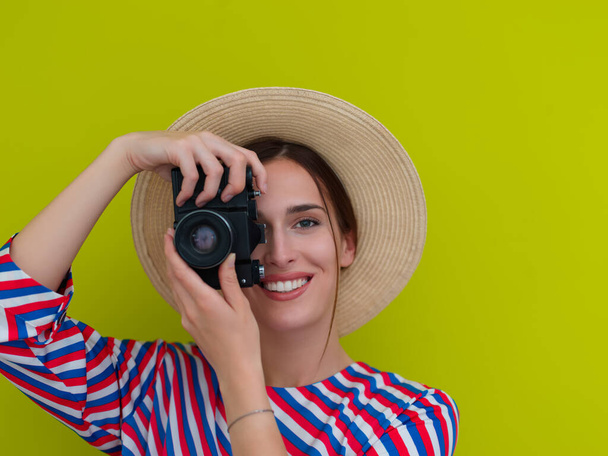 Портрет красивой женщины фотограф съемки крупным планом. Скажи сыр. Молодая улыбающаяся женщина держит камеру изолированной на зеленом фоне - Фото, изображение