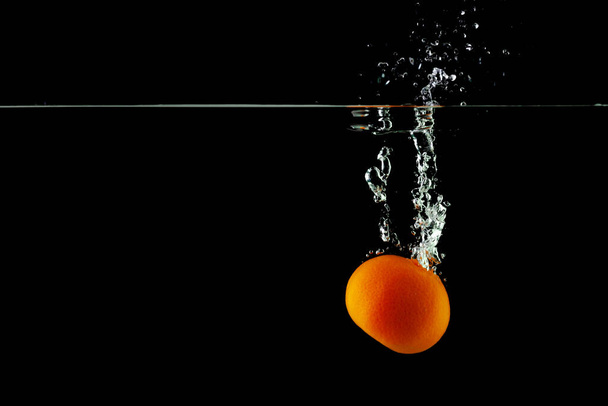 tangerine in water on a black background, place under the text - Foto, Imagen
