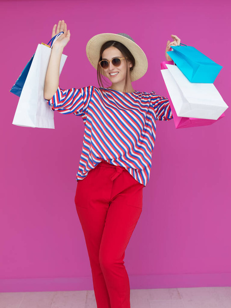 Young woman with shopping bags on pink background. Happy girl posing with new purchases after a day of big sale. Black Friday concept - Fotografie, Obrázek