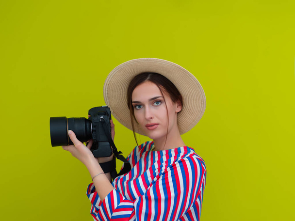 Portrait of beautiful female photographer close up. Say cheese. Young smiling woman holding camera and thinking how to make photo isolated on green background. - Фото, зображення