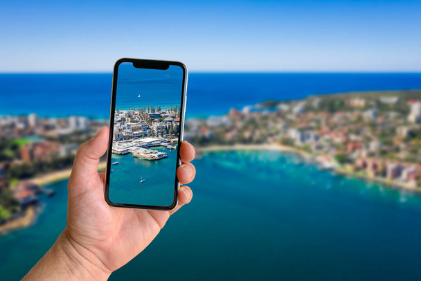 Man neemt foto met mobiele telefoon met wazig landschap op de achtergrond, close-up van de hand. Ruimte voor tekst - Foto, afbeelding