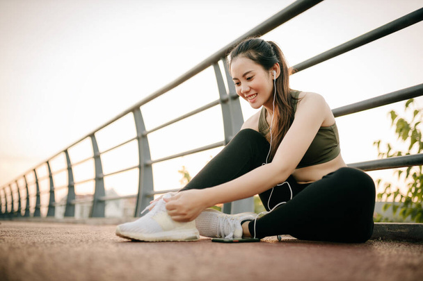 Beautiful asian women in sportswear Listening to music during exercise outdoors in the park at sunset. Healthy women concept. - Φωτογραφία, εικόνα