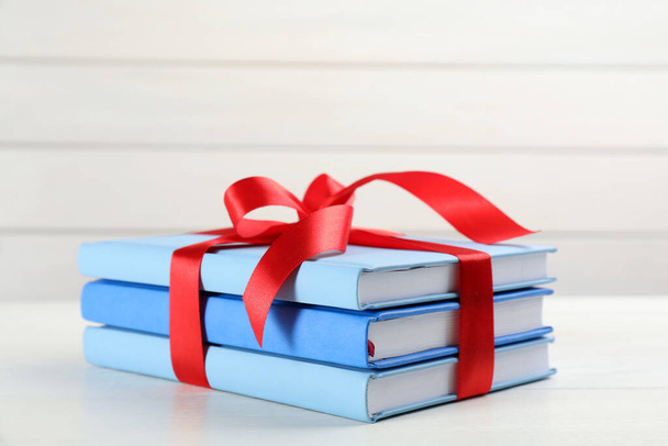 Different books tied with red ribbon on white table - Photo, Image