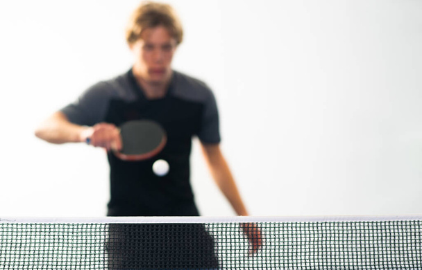 Tischtennis in Aktion, Fokus auf Netz und weißen Ball - Foto, Bild