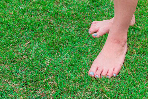 Naisen jalka seistä tuoretta vihreää ruohoa taustalla - Valokuva, kuva