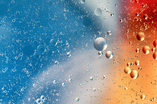 A closeup shot of water droplets on the colorful surface - 写真・画像