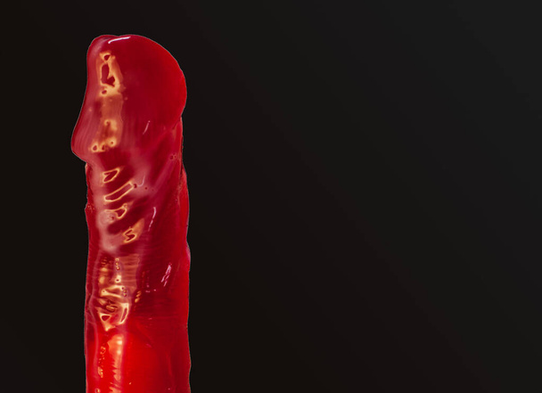 A red dildo on a black background. Gel for sex, lubrican - Fotografie, Obrázek