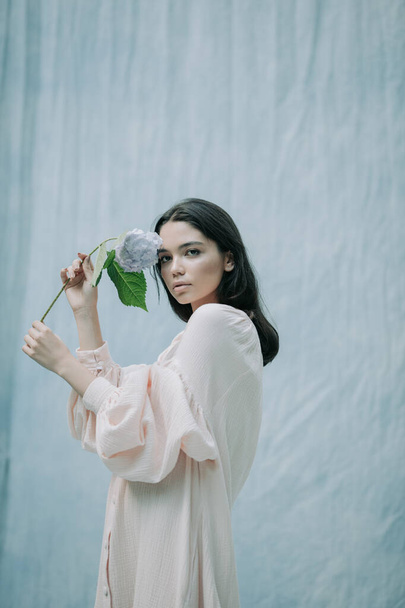 cute young woman posing with hydrangea flowers against cloth background  - Zdjęcie, obraz