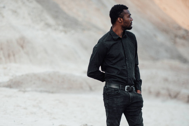 young  african american man in black shirt posing against granite canyon  - Fotoğraf, Görsel