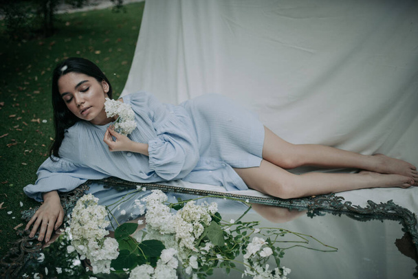 ritratto di una bella giovane donna in posa con dei fiori in un parco - Foto, immagini