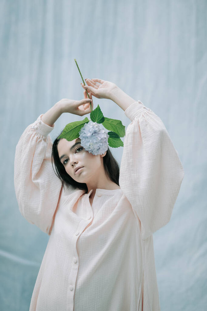 portrait of tender woman posing with hydrangea flowers against cloth background  - Фото, зображення