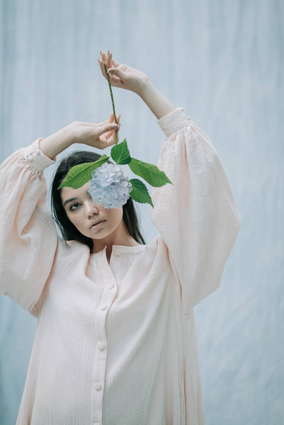 retrato de mujer tierna posando con flores de hortensias sobre fondo de tela  - Foto, Imagen