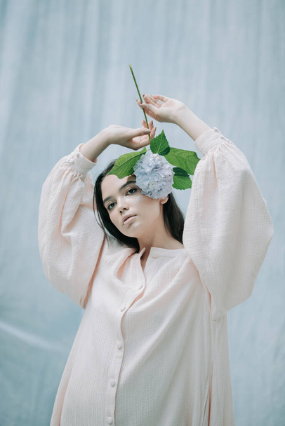 cute young woman posing with hydrangea flowers against cloth background  - Φωτογραφία, εικόνα