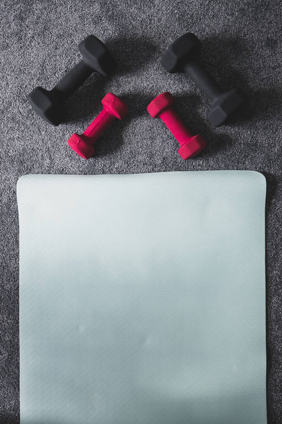 home gym with mixed fitness items including yoga mat and different sets of dumbbells on the floor - 写真・画像