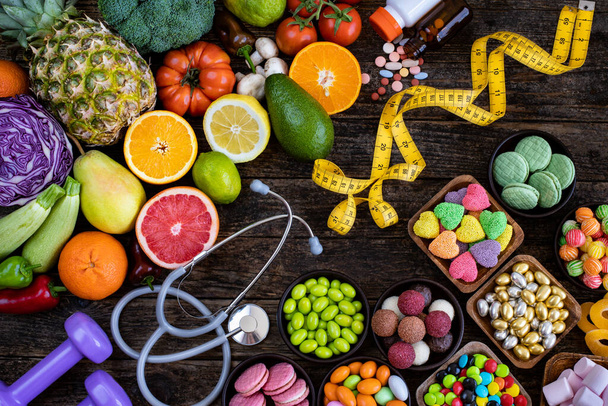 Zdrowe odżywianie vs niezdrowe odżywianie z pigułek, stetoskop i taśma miernika na stole. Koncepcja zdrowego stylu życia.  - Zdjęcie, obraz