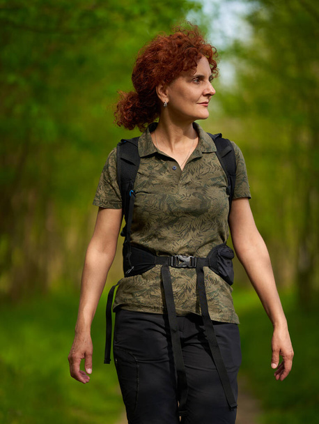 Active caucasian woman with backpack hiking into the forest - Fotoğraf, Görsel
