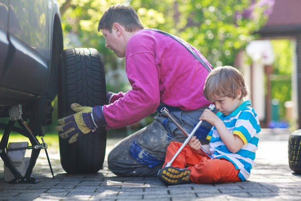Father and adorable little boy repairing car and changing wheel  - Foto, Imagen