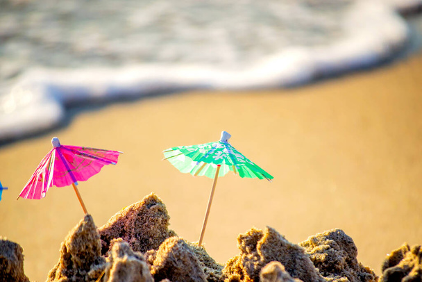 Small beach umbrellas made of paper for cocktail stand in sand - Photo, Image
