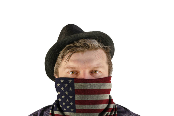 Muž středního věku v černém klobouku s malým okrajem a šátkem přes obličej. Šátek s obrázkem vlajky USA. Nerozpoznatelná osoba na bílém pozadí. - Fotografie, Obrázek