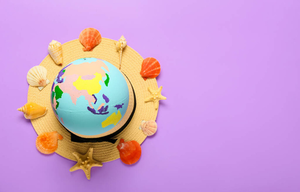 Globe with hat and seashells on color background - Fotoğraf, Görsel
