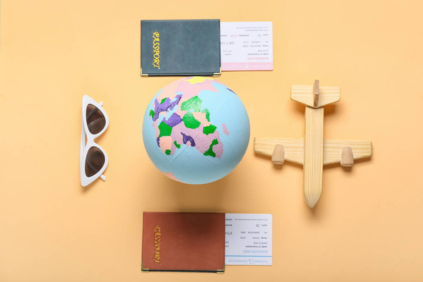 Tahta uçak, güneş gözlüğü, pasaport ve renkli arka plan biletleri olan dünya. - Fotoğraf, Görsel