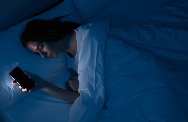 Woman sleeping with smartphone in bed - 写真・画像