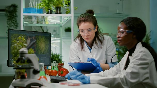Kaksi kollegiota tarkastamassa otosta vegaanilihasta kirjoittamassa biotekniikan asiantuntemusta - Valokuva, kuva