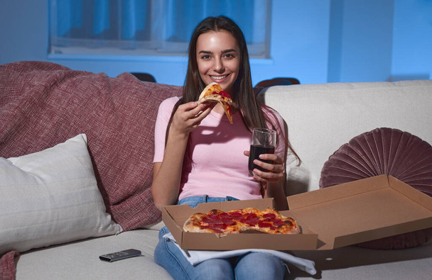 Cheerful woman with pizza and drink watching movie - Valokuva, kuva